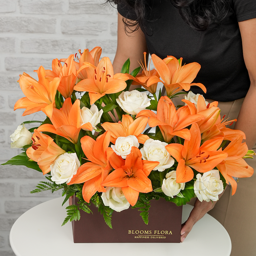 7 orange lilies and 10 white roses in a box