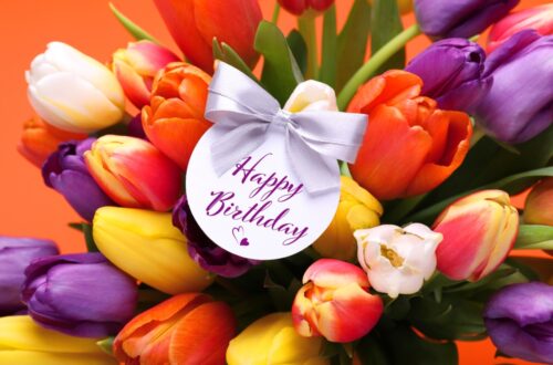 Happy birthday flowers tag on a bunch of white pink purple yellow and orange tulips